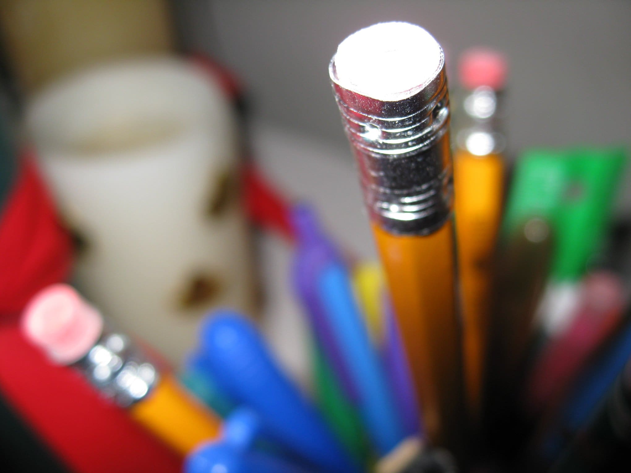 Close-up photo of pencils and pens in a holder, featuring vibrant colors.