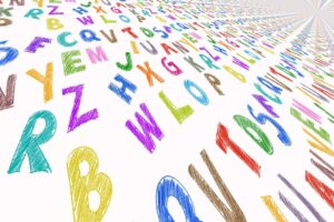 Colorful alphabet letters scattered diagonally, crayon style on white background.