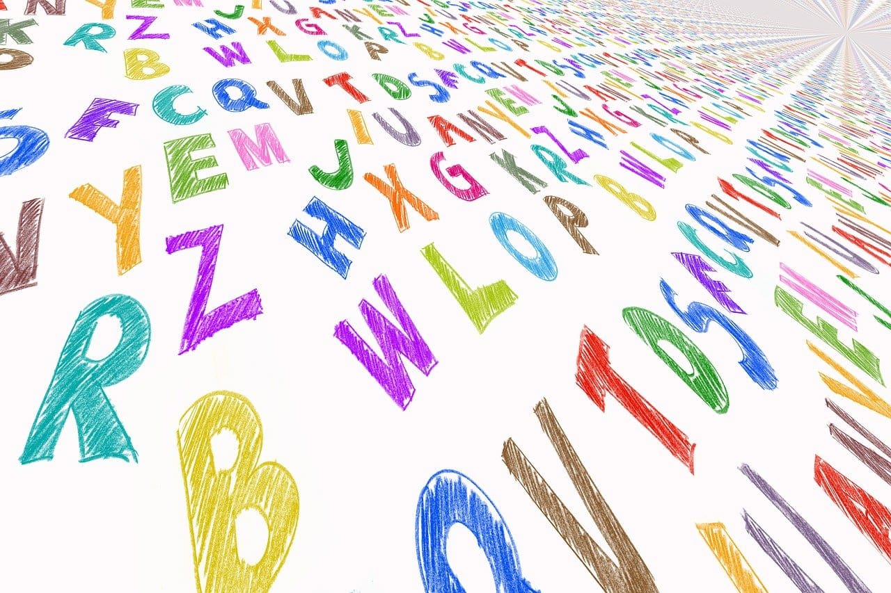 Colorful alphabet letters scattered diagonally, crayon style on white background.