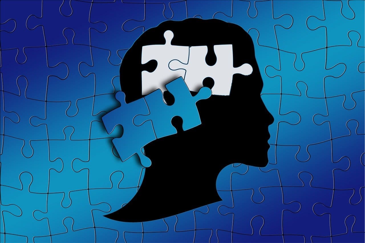 Silhouette of head with puzzle pieces, blue gradient background, digital illustration.