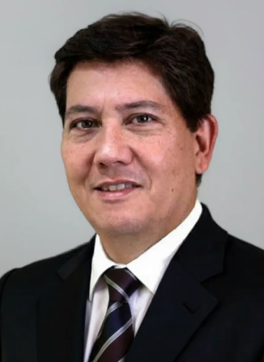Man smiling in a black suit with striped tie, portrait photograph.